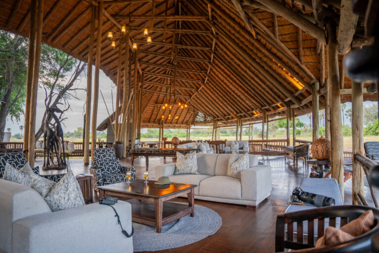 Spacious open-air lounge with thatched roof and sofas at Moremi Crossing.