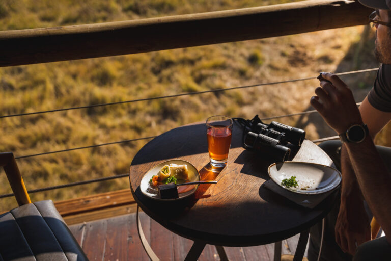 Guest enjoying breakfast and tea on a wooden deck overlooking the Okavango Delta.