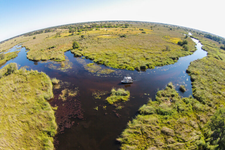Aerial view of boat cruising through Okavango Delta channels near Kwara Camp.