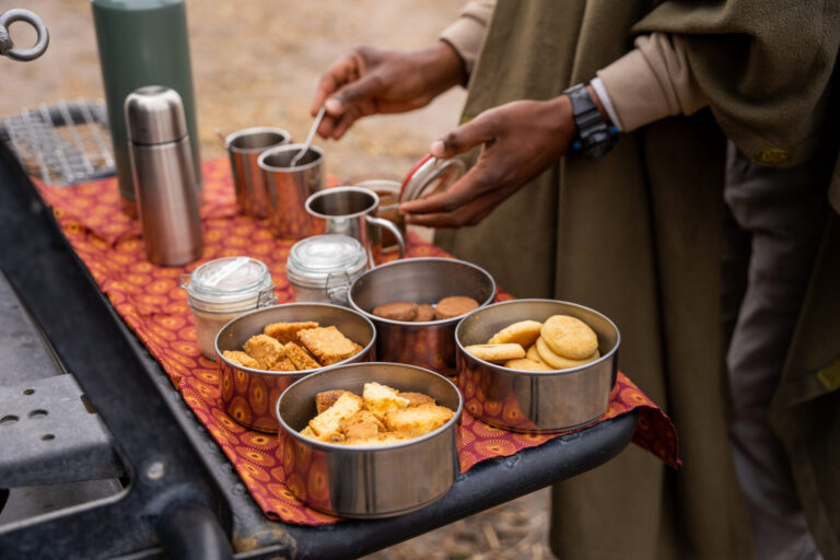 Safari guide preparing coffee and biscuits during a morning break in the bush.