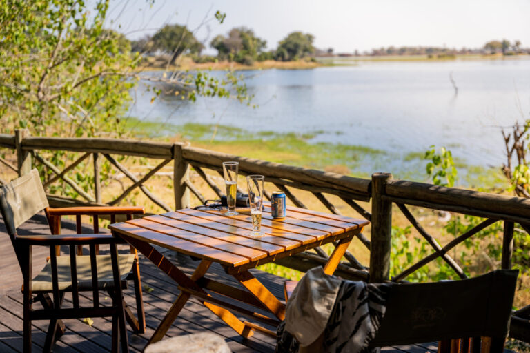 Wooden deck table with chairs overlooking the lagoon at Pom Pom Camp.