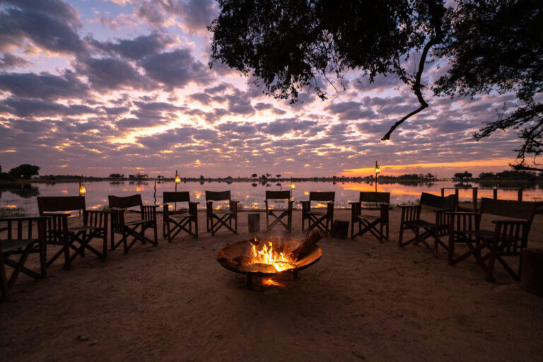 Firepit with chairs and sunset reflections over the lagoon at Pom Pom Camp.