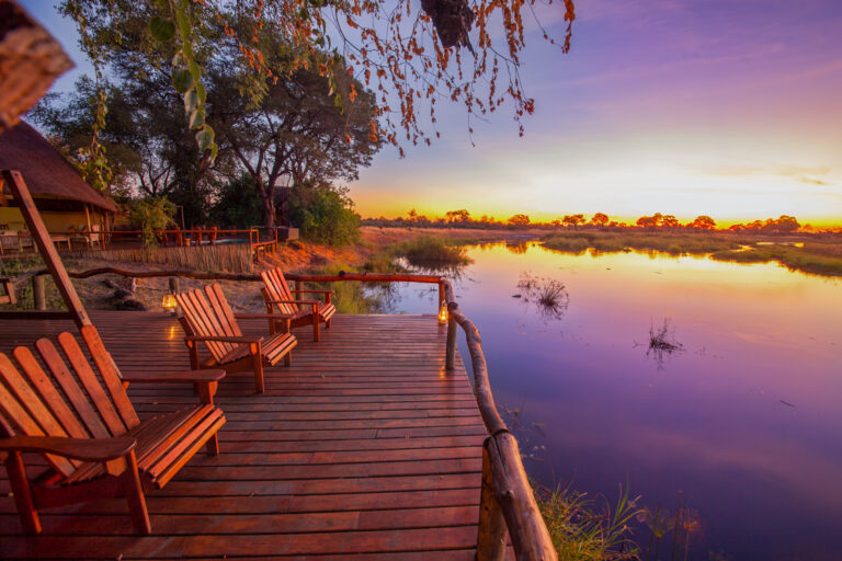 Wooden deck with chairs overlooking a calm river at sunset in Lagoon Camp.