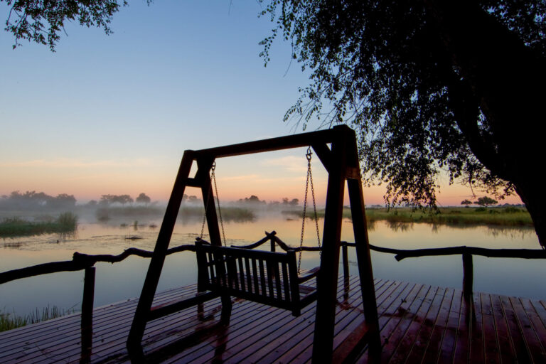 Wooden swing facing a misty river at sunrise in Lagoon Camp.