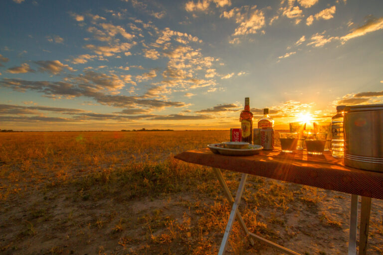 Table with drinks and snacks at sunset on the open plains near Nxai Pan Camp.