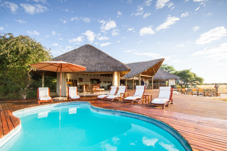 Swimming pool and wooden sun deck with loungers at Nxai Pan Camp.