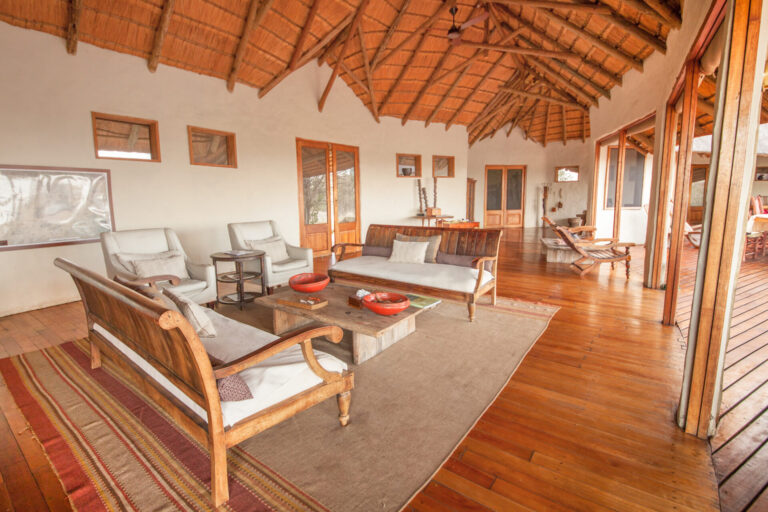 Open-plan lounge with wooden furniture and thatched ceiling at Tau Pan Camp.