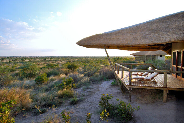 Guest relaxing on a deck chair overlooking the arid landscape at Tau Pan Camp.