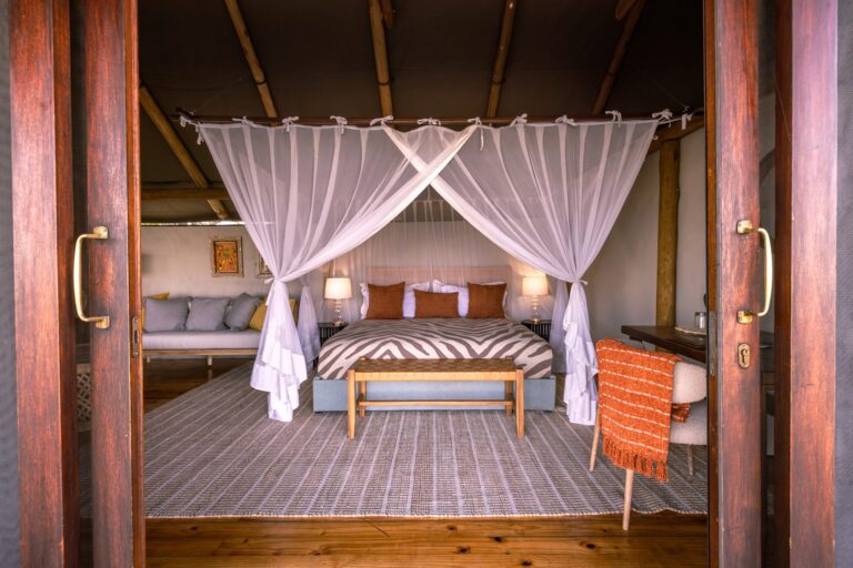 Double bed with mosquito net in large suite of Okavango Delta Safaris.