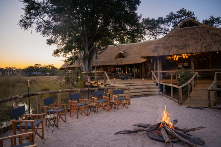 Firepit area with chairs in front of main lodge at dusk at Four Rivers Camp.