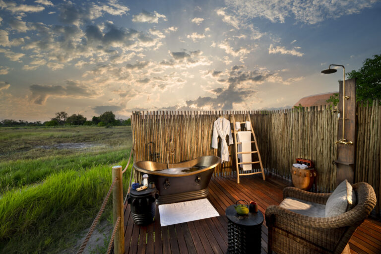 Outdoor bathtub and shower on wooden deck overlooking Okavango Delta grasslands in Botswana.