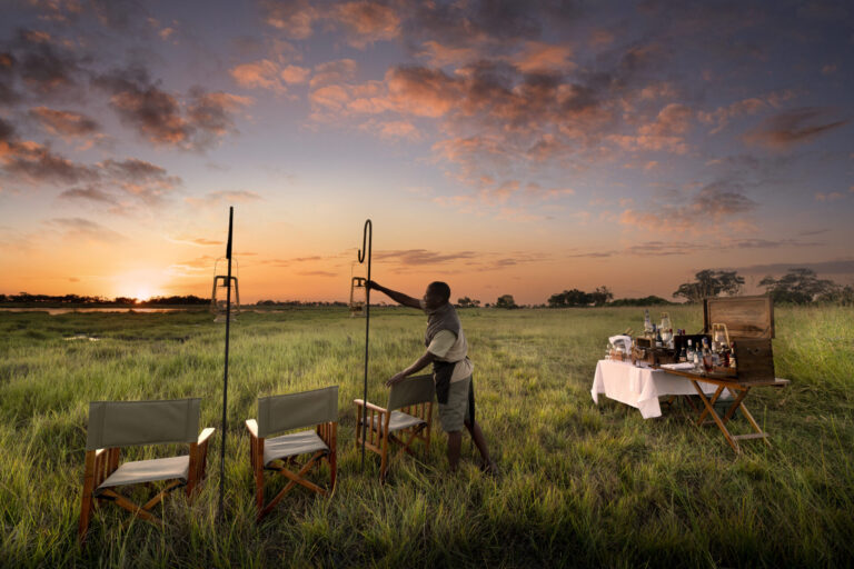 Sunrise bush breakfast with chairs and table setup in the Okavango Delta at Atzaró Okavango Camp.