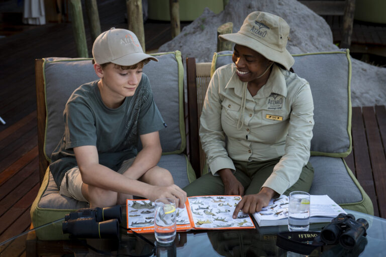 Safari guide teaching a young guest about wildlife at Atzaró Okavango Camp in Botswana.