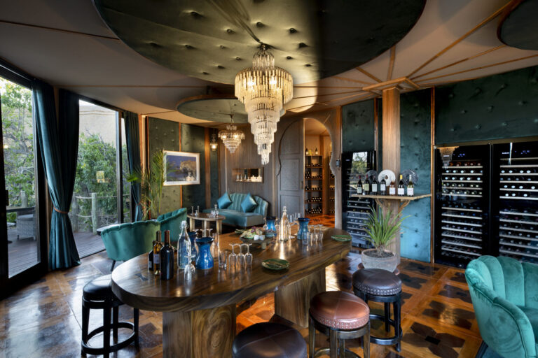 Atzaró Okavango Camp wine lounge with chandelier, bar table, and wine display in Botswana.