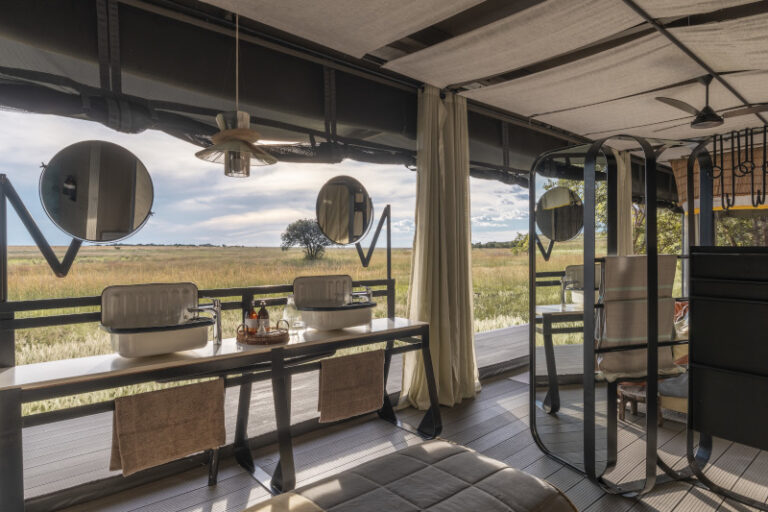 Guest bathroom at King Lewanika Lodge with twin basins and panoramic views of Liuwa Plain