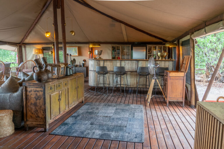 Bar and lounge area at Linyanti Bush Camp in Botswana with wooden floors and canvas tent design.